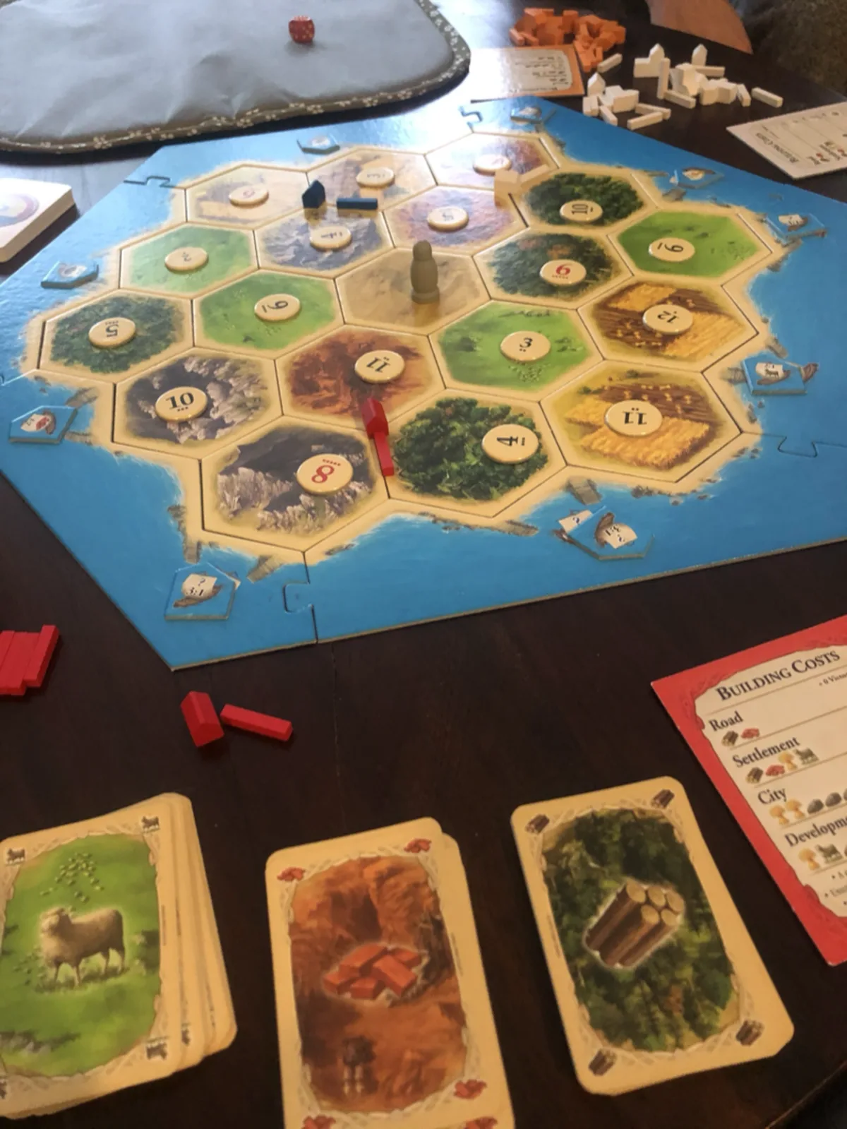A game of Catan in progress, friends gathered around the table for an evening of play